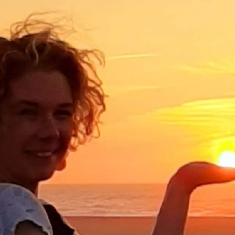 Clare Reynolds outdoors at sunset with the ocean behind her